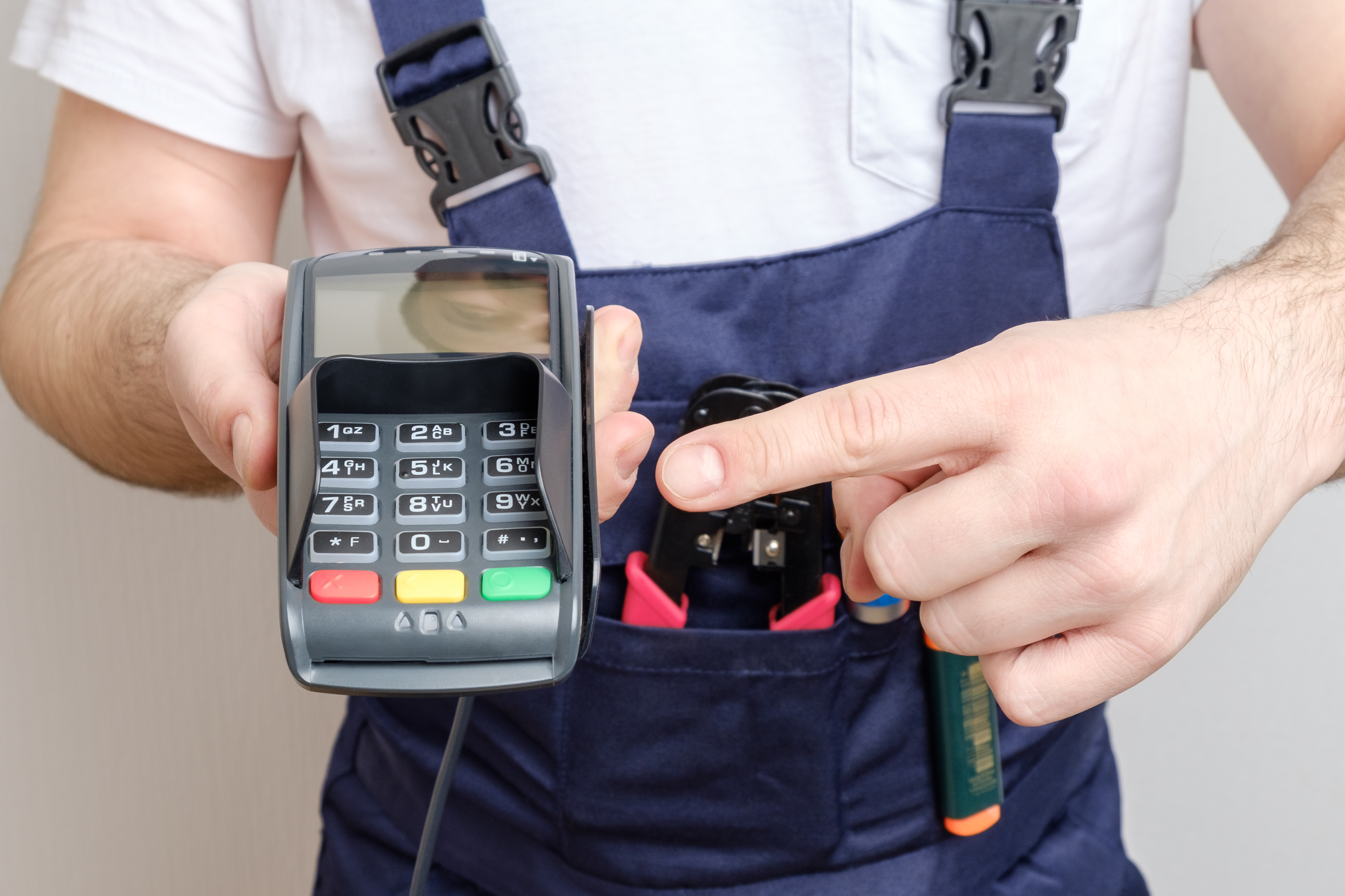 Man with tools holding bank payment terminal. Salary concept